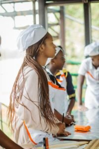 Culinary students attentively listening during a cooking class, wearing chef hats.