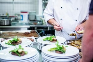 A chef prepares gourmet dishes in a professional kitchen setting, showcasing fine dining elegance.